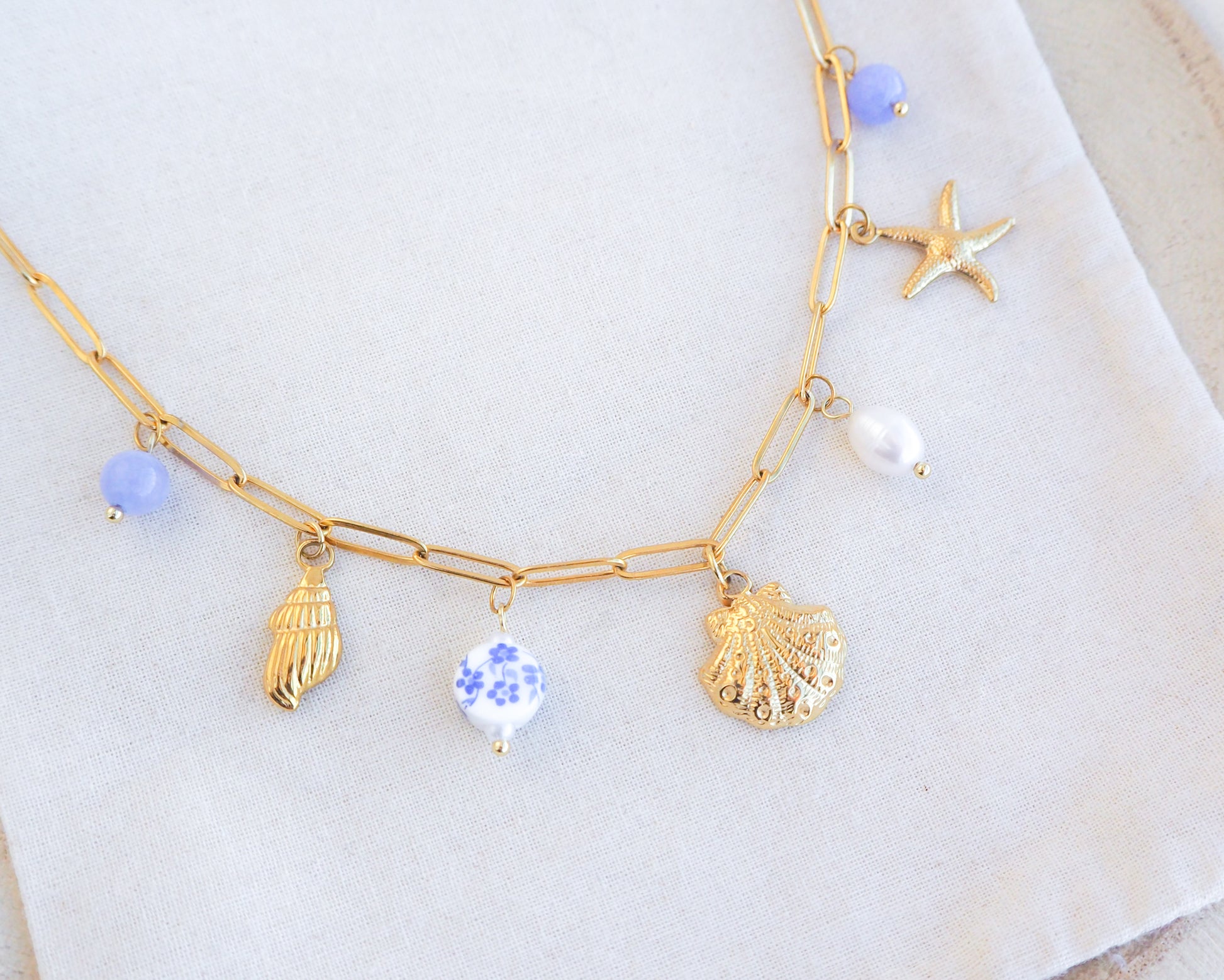 Oceanic Charm Necklace with Shells and Starfish Pendants, Freshwater Pearls and Gemstones on display