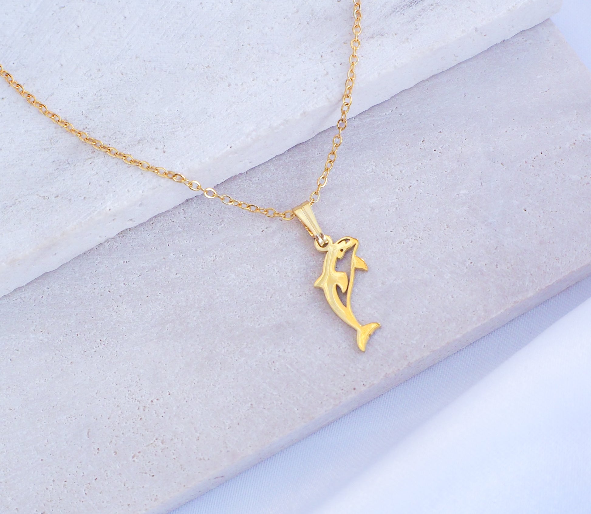 Gold Orca Killer Whale Necklace displayed on stone