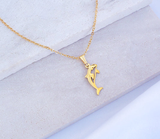 Gold Orca Killer Whale Necklace displayed on stone