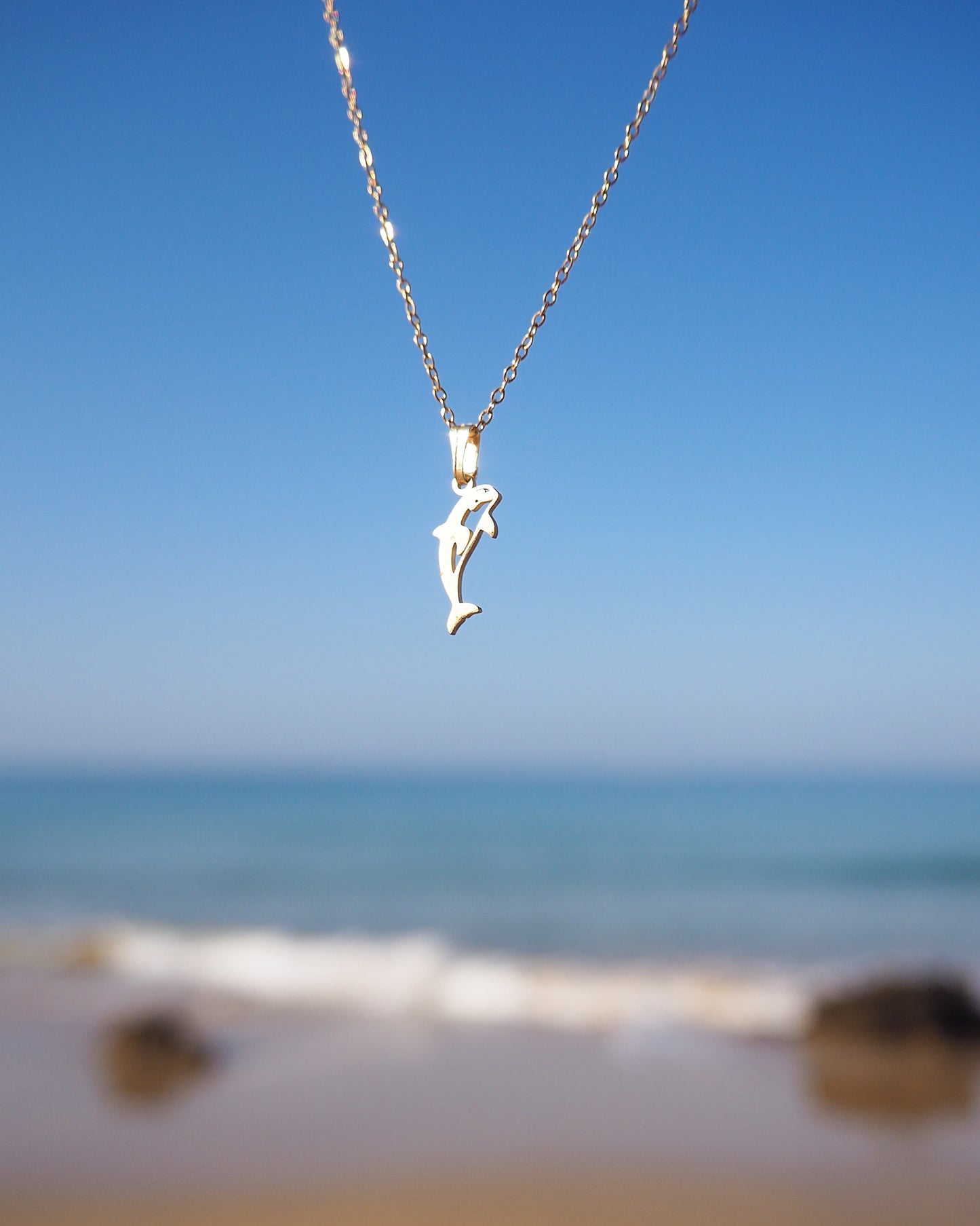 Gold Orca Killer Whale Necklace with blue ocean view background 
