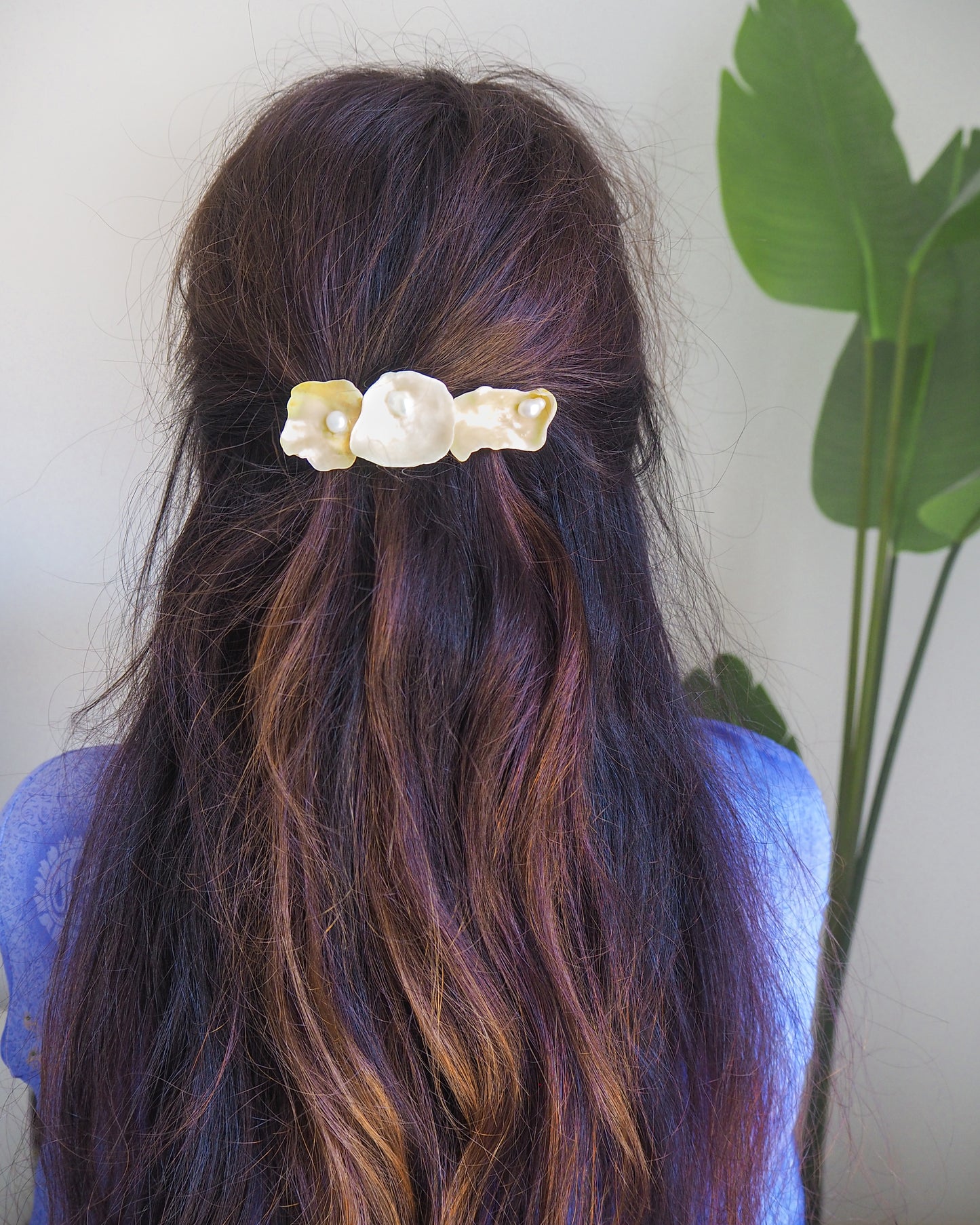 Hair clip with pearls and shells in a person's hair against a neutral background. Pearl oyster shell hair clip in brown long hair model. Made with handpicked jingle shells saddle oysters from Portugal. The hair clips has 3 shells with a soft yellow color. Jingle Shell Pearl Hair clip. Boho Seashell Beach Clip from Portugal, Handpicked Real Shells, Seashell Hair Decoration, Bohemian Seashell Wedding Hair accessories, Coastal Christmas gift, Beach Wedding Hair