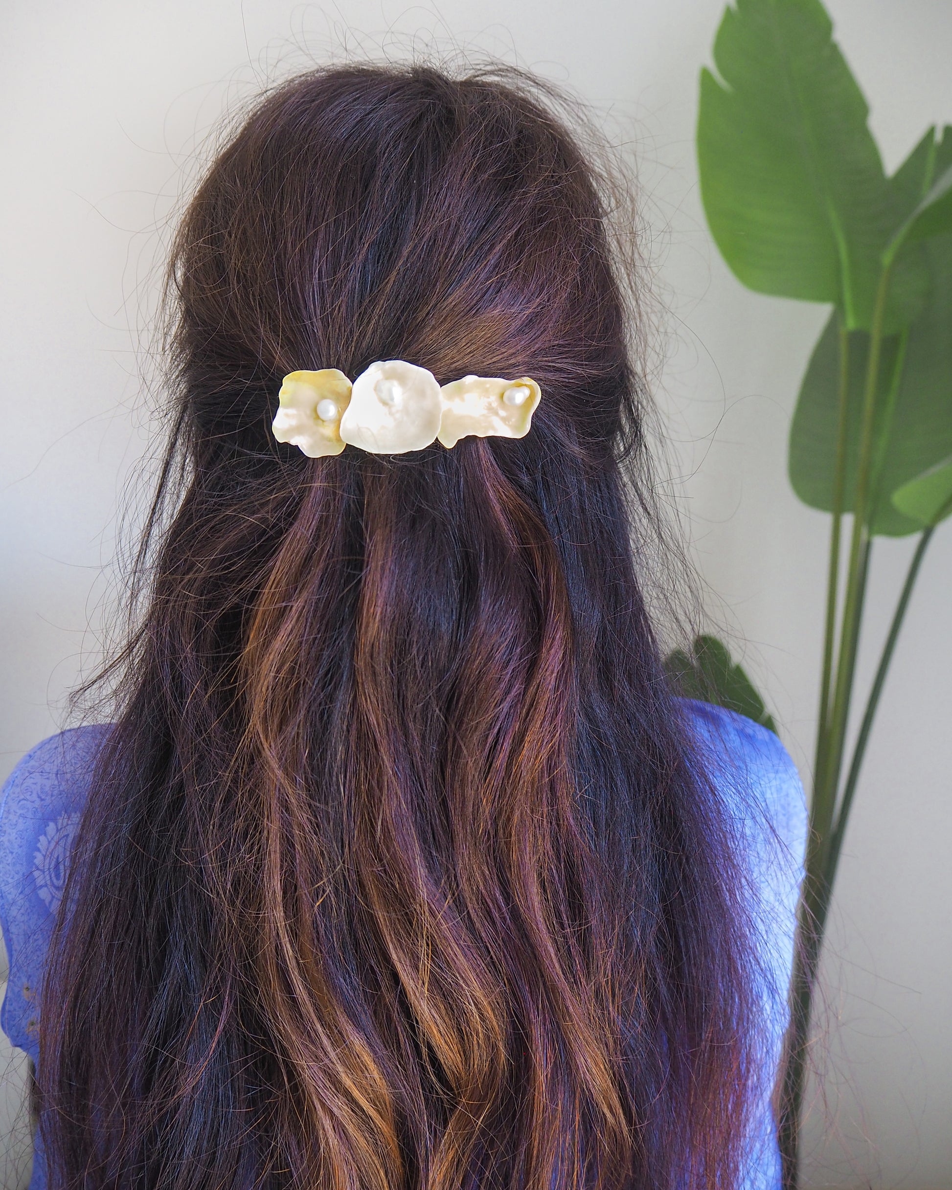 Hair clip with pearls and shells in a person's hair against a neutral background. Pearl oyster shell hair clip in brown long hair model. Made with handpicked jingle shells saddle oysters from Portugal. The hair clips has 3 shells with a soft yellow color. Jingle Shell Pearl Hair clip. Boho Seashell Beach Clip from Portugal, Handpicked Real Shells, Seashell Hair Decoration, Bohemian Seashell Wedding Hair accessories, Coastal Christmas gift, Beach Wedding Hair