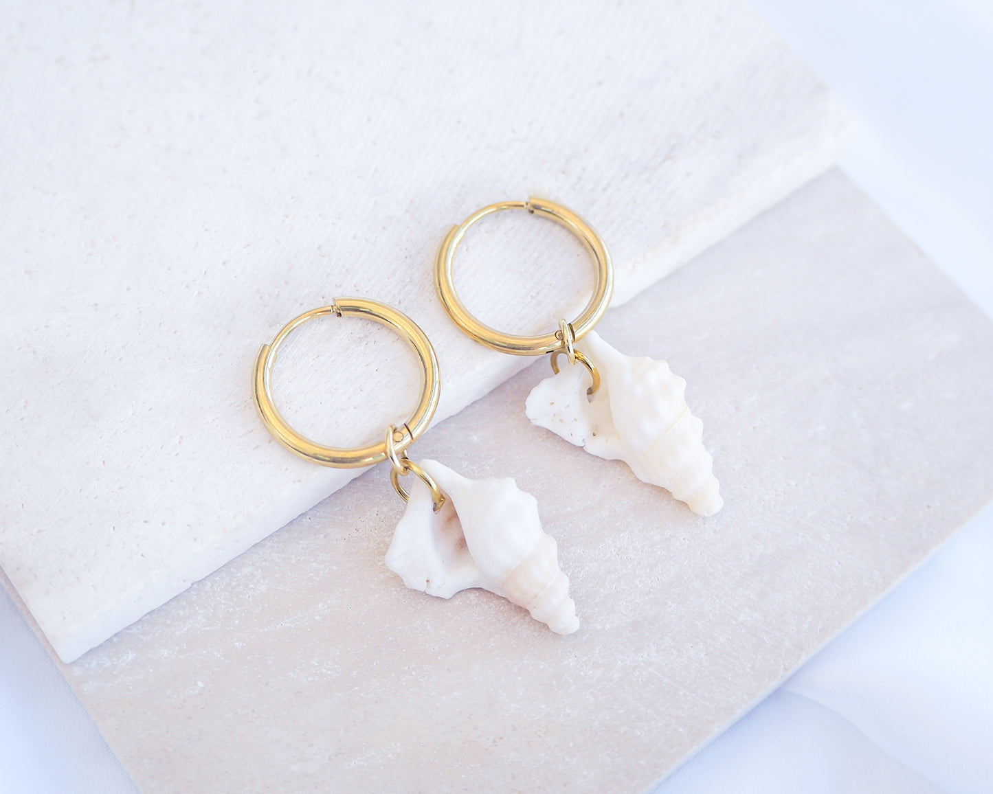 Pelicans Foot Shell Gold Earring Hoops displayed on stone, handpicked white pelican foot shells from Portugal, 18k gold stainless steel shell earring hoops, seabylou 