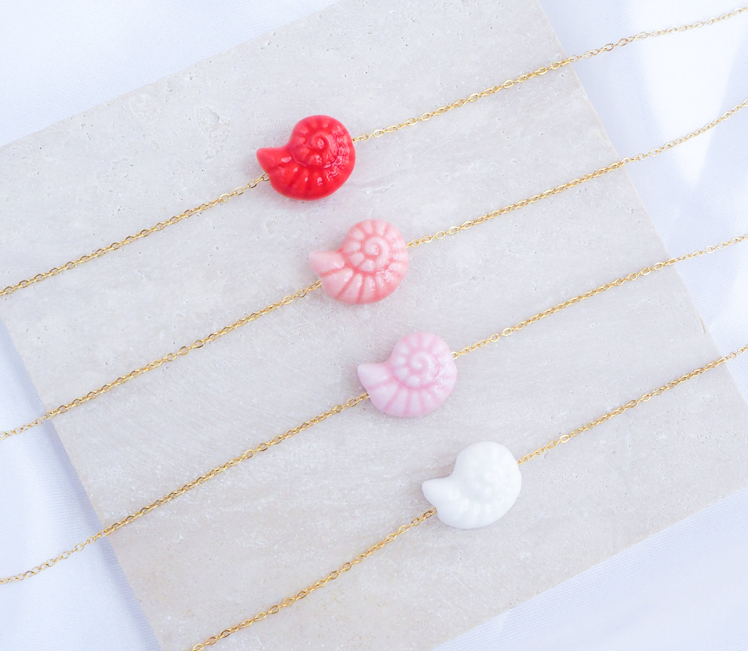 Pink Red Coral Seashell Ceramic Nautilus Gold Necklaces on display 