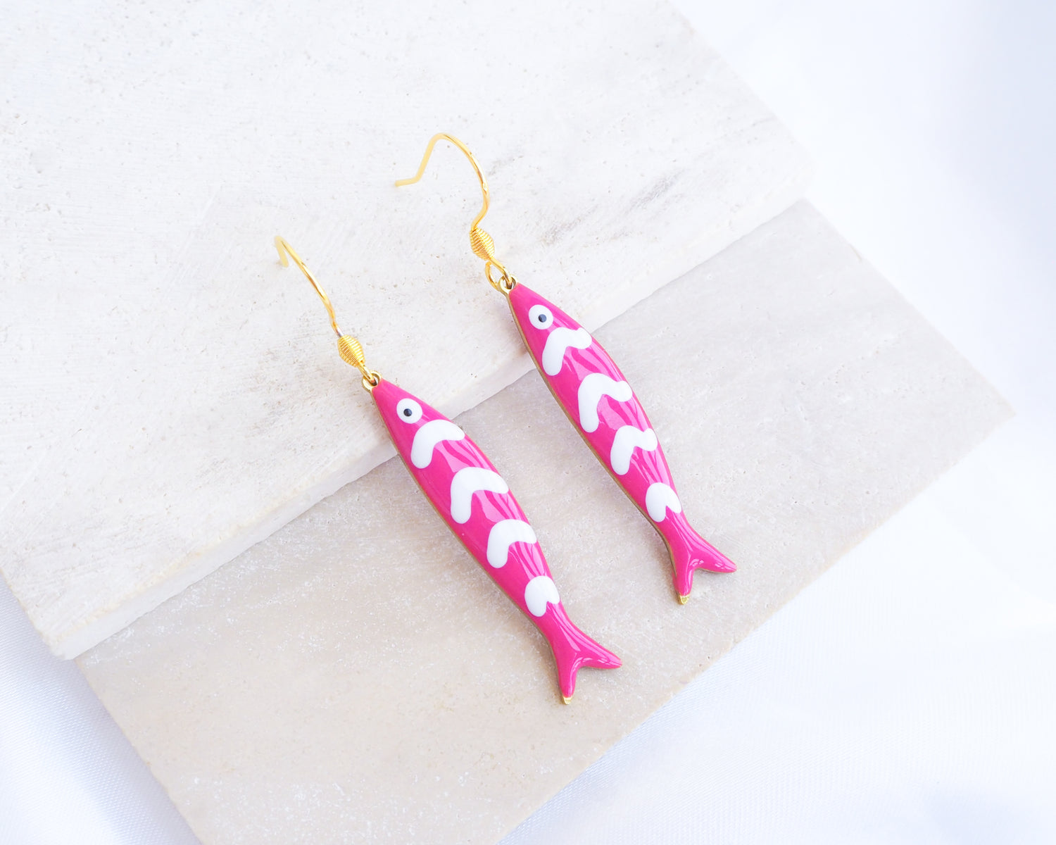 Pink Sardine Fish Earrings with 14k gold stainless steel earring hooks displayed on stone, Beautiful gift for Portugal lovers or holiday memory, coastal jewelry from Portugal
