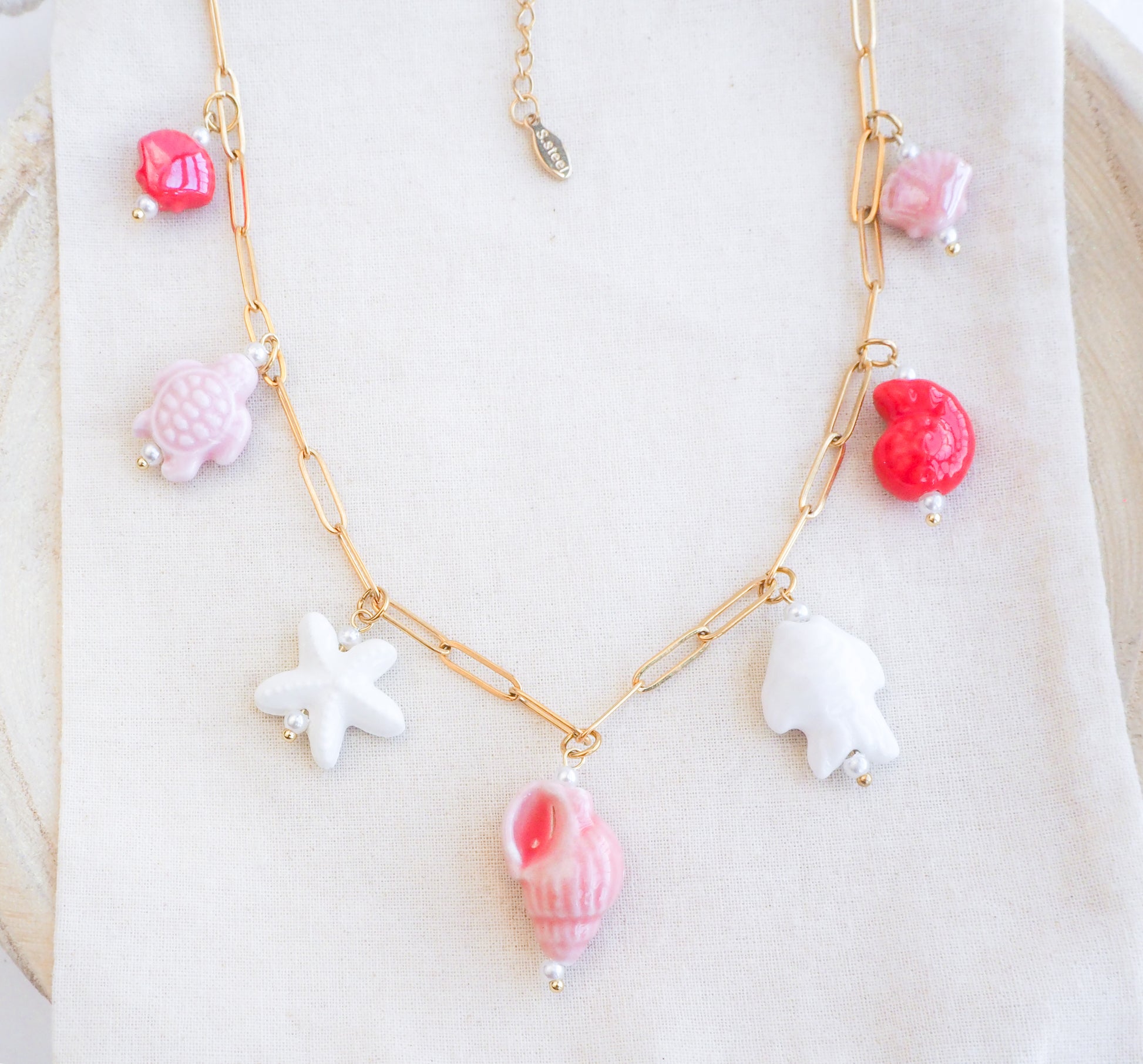 Front view of Sweet Ocean Ceramic Charm Necklace with 7 ceramic ocean charms (turtle, starfish, fish, shell & more), Pink white red sea pendants, 18k gold stainless steel chain 