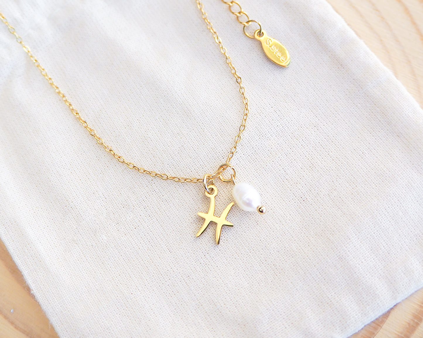 Close up of Gold Pisces Zodiac Pearl Necklace on display, made with 18k gold stainless steel and white freshwater pearl 