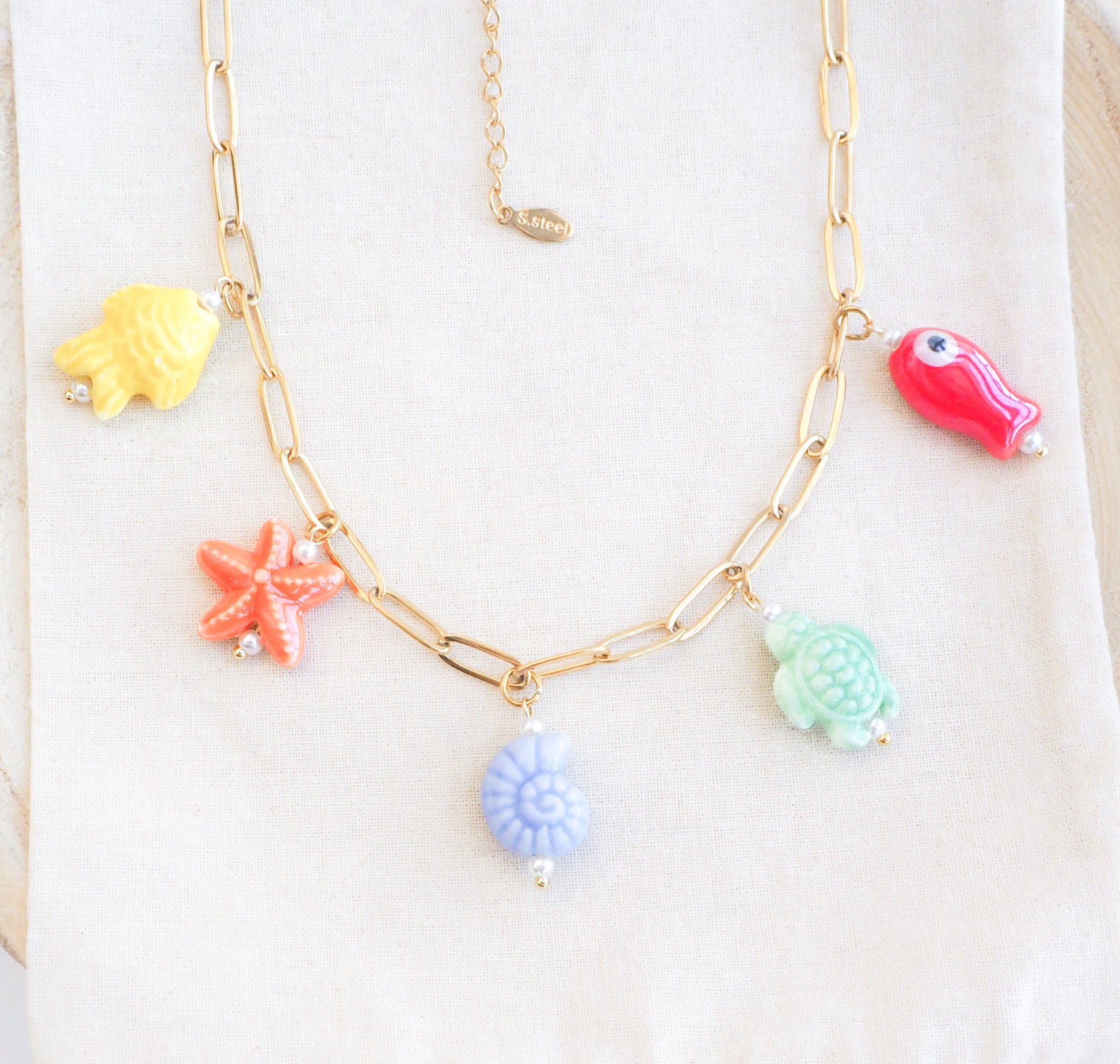 Front view of Rainbow Ceramic Charm Necklace with 5 ceramic ocean charms (turtle, starfish, fish, shell & more), sea treasure pendants, 18k gold stainless steel chain displayed 