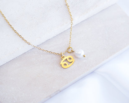 Gold Cancer Zodiac Pearl Necklace on stone displayed, made with 18k gold stainless steel and white freshwater pearl 