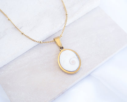 Gold necklace with a pendant on a white background. White Eye of Saint Lucia Gold Necklace on stone displayed, 18k gold stainless steel shiva eye pendant necklace, Saint Lucy Eye, operculum pendant