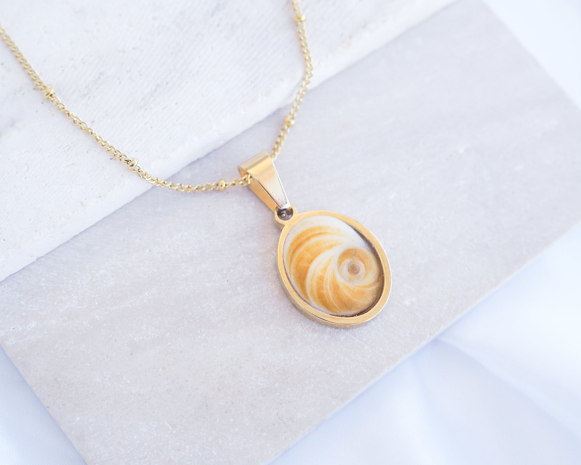 Yellow Orange Eye of Saint Lucia Gold Necklace on stone displayed, 18k gold stainless steel shiva Yellow Orange eye pendant necklace, Saint Lucy Eye, operculum pendant