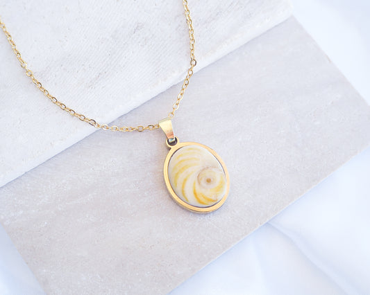 Soft Yellow Shiva Eye Gold Necklace on stone displayed. Light Eye of Saint handpicked from Portugal, 18k gold stainless steel shiva eye pendant necklace, Saint Lucy Eye, operculum pendant