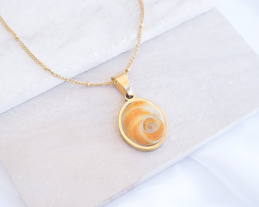Gold Yellow Orange Shiva Eye, Eye of Saint Lucia Gold Necklace on stone displayed, 18k gold stainless steel shiva Yellow Orange eye pendant necklace, Saint Lucy Eye, operculum pendant
