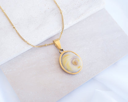Soft Yellow Shiva Eye Necklace III on stone displayed. Light Eye of Saint handpicked from Portugal, 18k gold stainless steel shiva eye pendant necklace, Saint Lucy Eye, operculum pendant