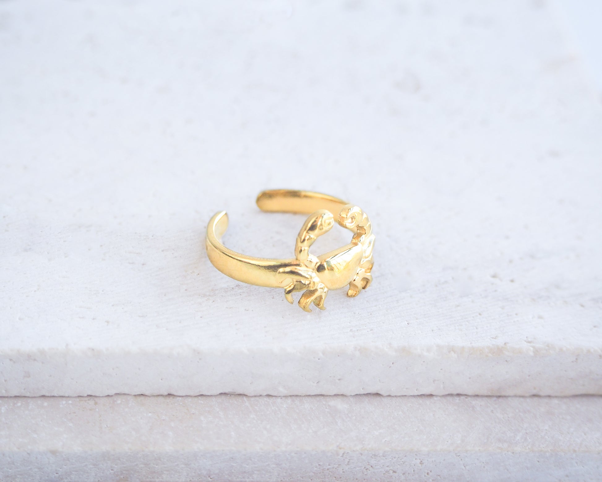Gold crab-shaped ring on a light gray background. Side view of Gold Cancer Zodiac Ring on stone displayed, adjustable 18k gold stainless steel crab ring 