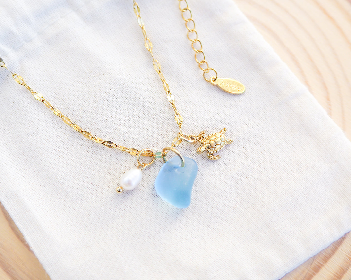 Tiny Turtle Blue Sea Glass Pearl Necklace on light cotton displayed, tiny turtle necklace, ocean blue necklace, coastal jewelry, freshwater pearl necklace, gold turtle necklace 