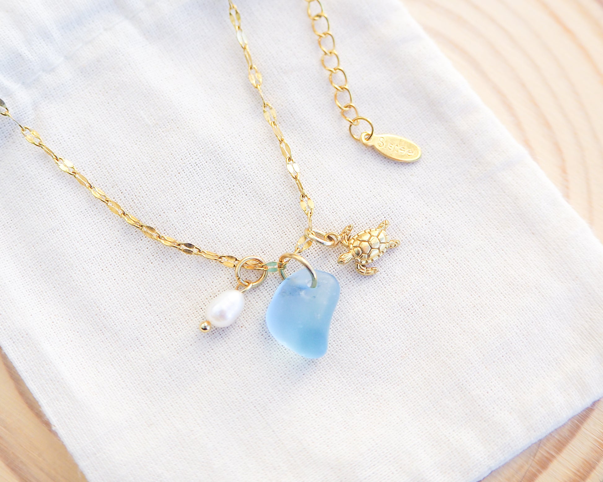 Tiny Turtle Blue Sea Glass Pearl Necklace on light cotton displayed, tiny turtle necklace, ocean blue necklace, coastal jewelry, freshwater pearl necklace, gold turtle necklace 