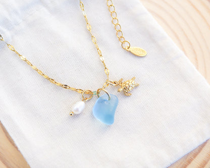 Tiny Turtle Blue Sea Glass Pearl Necklace on light cotton displayed, tiny turtle necklace, ocean blue necklace, coastal jewelry, freshwater pearl necklace, gold turtle necklace 