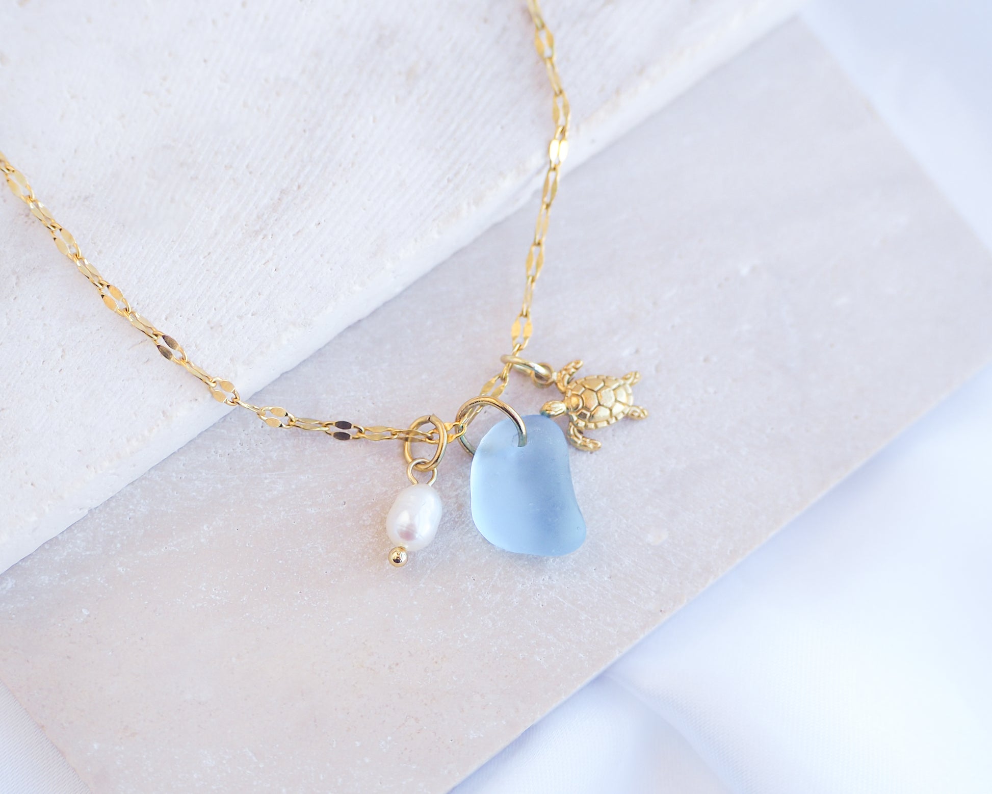Tiny Turtle Blue Sea Glass Pearl Necklace on stone displayed, tiny turtle necklace, ocean blue necklace, coastal jewelry, freshwater pearl necklace, gold turtle necklace 