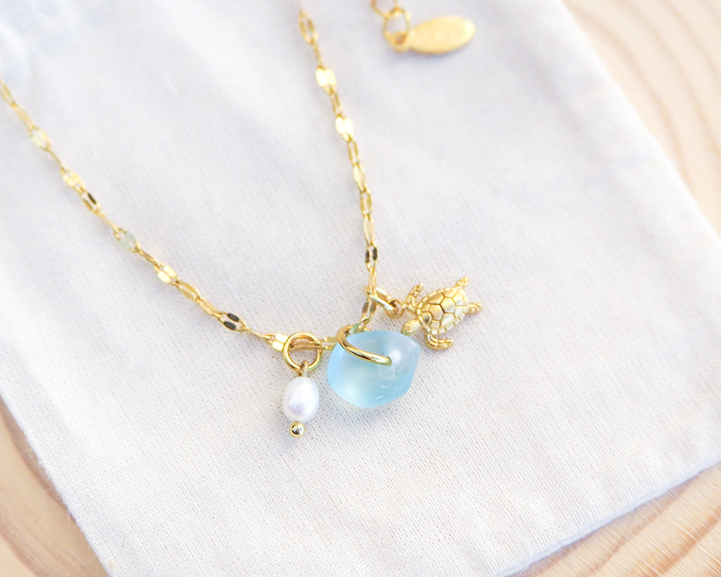 Close up of Tiny Turtle Blue Sea Glass Pearl Necklace II on cotton displayed, tiny turtle necklace, ocean blue necklace, coastal jewelry, freshwater pearl necklace, gold turtle necklace 