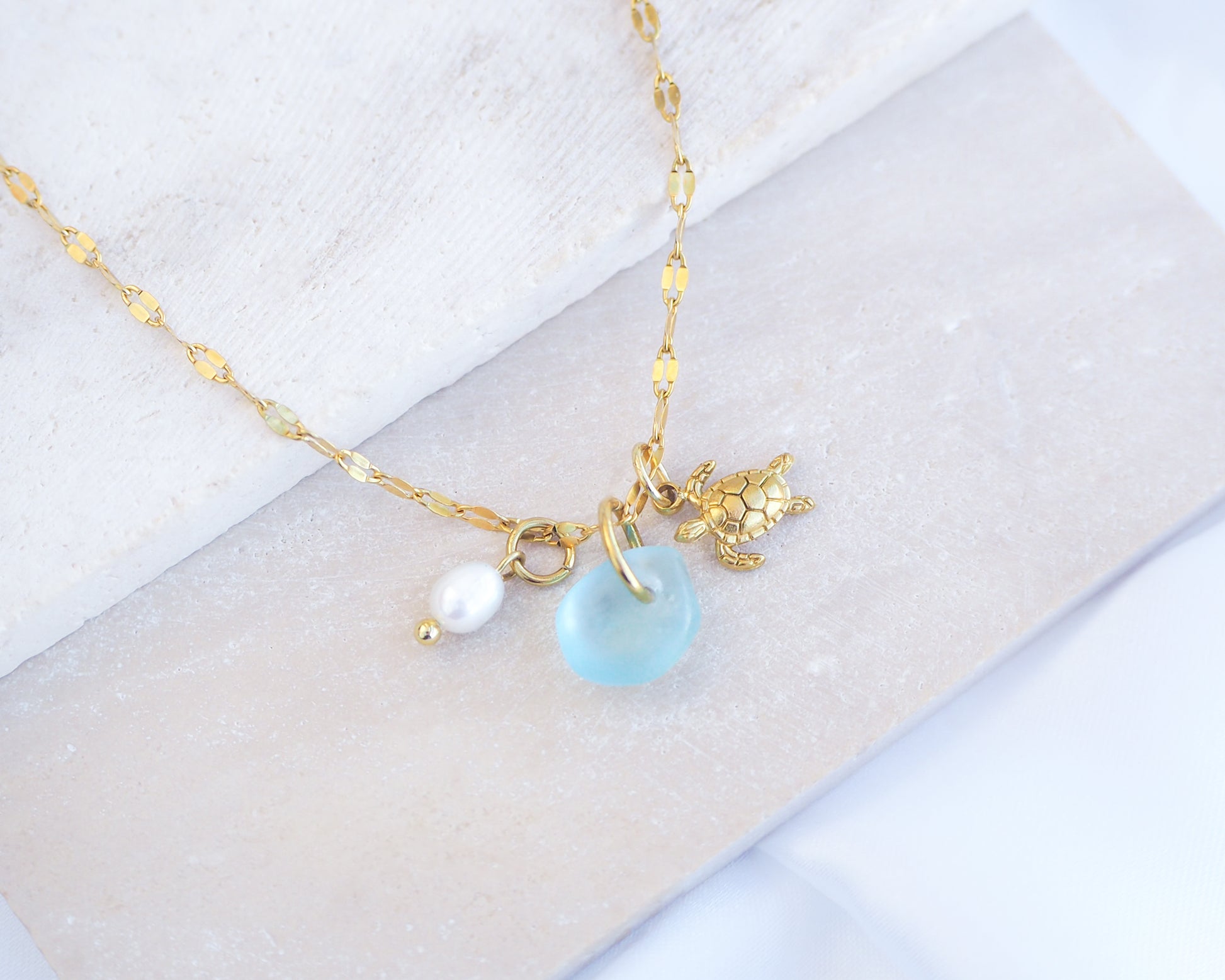 Tiny Turtle Blue Sea Glass Pearl Necklace II on stone displayed, tiny turtle necklace, ocean blue necklace, coastal jewelry, freshwater pearl necklace, gold turtle necklace 
