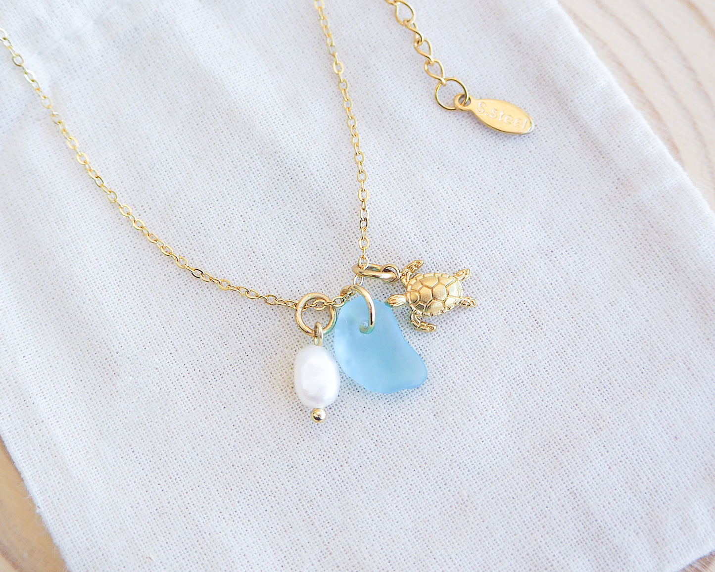 Tiny Sea Turtle Blue Sea Glass Pearl Necklace on cotton displayed, tiny turtle necklace, turquoise blue necklace, coastal jewelry, freshwater pearl necklace, gold turtle necklace 