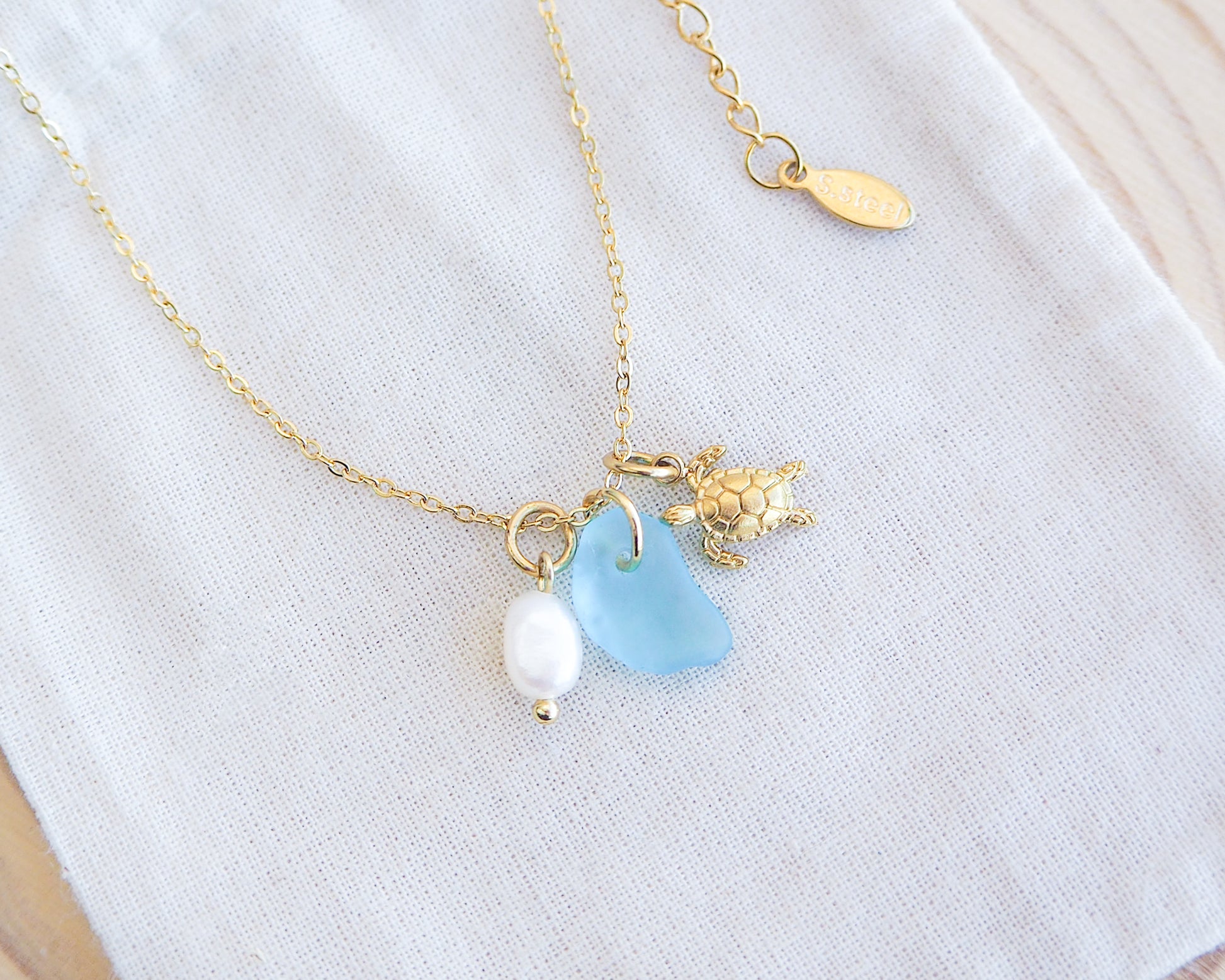 Tiny Sea Turtle Blue Sea Glass Pearl Necklace on cotton displayed, tiny turtle necklace, turquoise blue necklace, coastal jewelry, freshwater pearl necklace, gold turtle necklace 