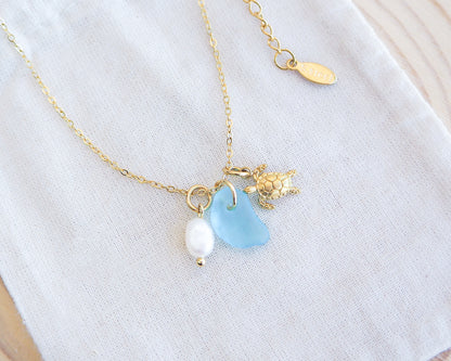Tiny Sea Turtle Blue Sea Glass Pearl Necklace on cotton displayed, tiny turtle necklace, turquoise blue necklace, coastal jewelry, freshwater pearl necklace, gold turtle necklace 