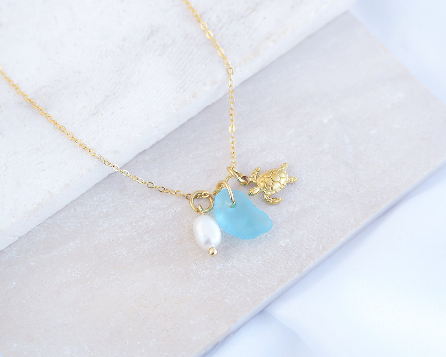 Tiny Sea Turtle Blue Sea Glass Pearl Necklace on stone displayed, tiny turtle necklace, turquoise blue necklace, coastal jewelry, freshwater pearl necklace, gold turtle necklace 