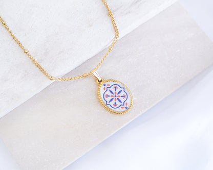 Close up of Blue Coral Portuguese Tile Oval Necklaces Blue on stone displayed. Made with 18k gold stainless steel and white blue mosaic pendant inspired by the Portuguese Azulejo design pattern. 