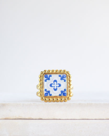 Blue White Gold Portuguese Tile Square Ring on stone displayed. Rings is handmade with 18k gold stainless steel and has a blue white floral tile pattern inspired by the Portuguese azulejos tiles. 