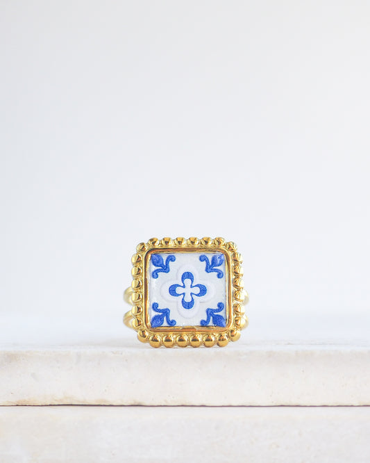 Blue White Gold Portuguese Tile Square Ring on stone displayed. Rings is handmade with 18k gold stainless steel and has a blue white floral tile pattern inspired by the Portuguese azulejos tiles. 