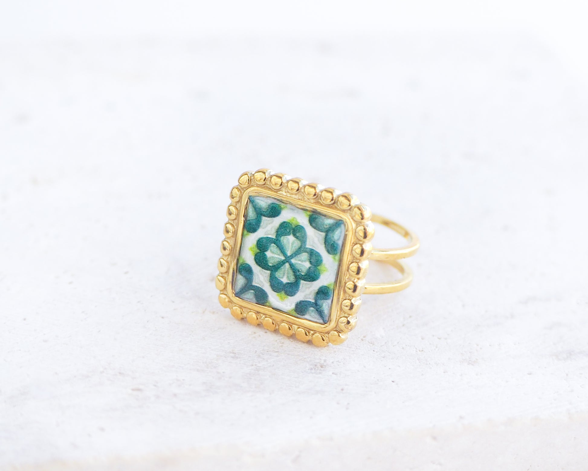Side view of Green Gold Portuguese Tile Square Ring on stone displayed. Rings is handmade with 18k gold stainless steel and has a green floral tile pattern inspired by the Portuguese azulejos tiles. 