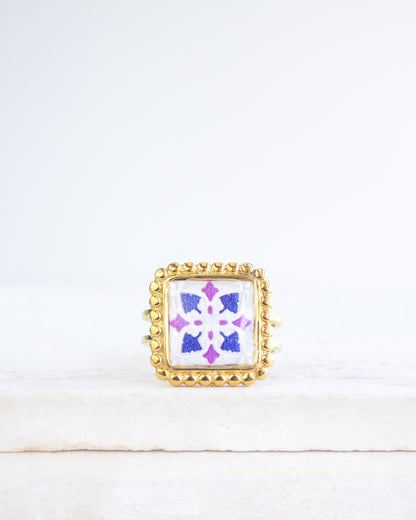 Purple Gold Portuguese Tile Square Ring on stone displayed. Rings is handmade with 18k gold stainless steel and has a purple and pink tile pattern inspired by the Portuguese azulejos tiles. 