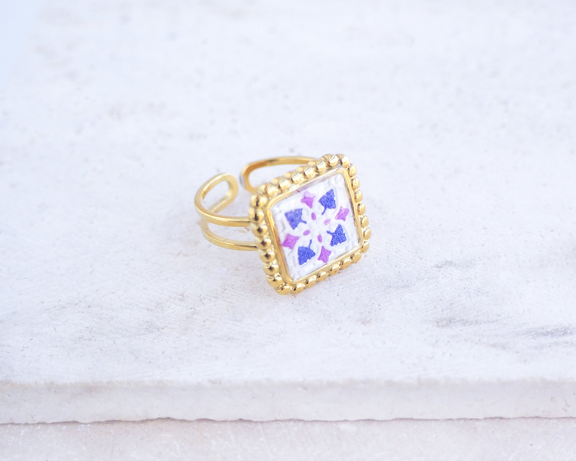 Side view of Purple Gold Portuguese Tile Square Ring on stone displayed. Rings is handmade with 18k gold stainless steel and has a purple pink tile pattern inspired by the Portuguese azulejos tiles. 