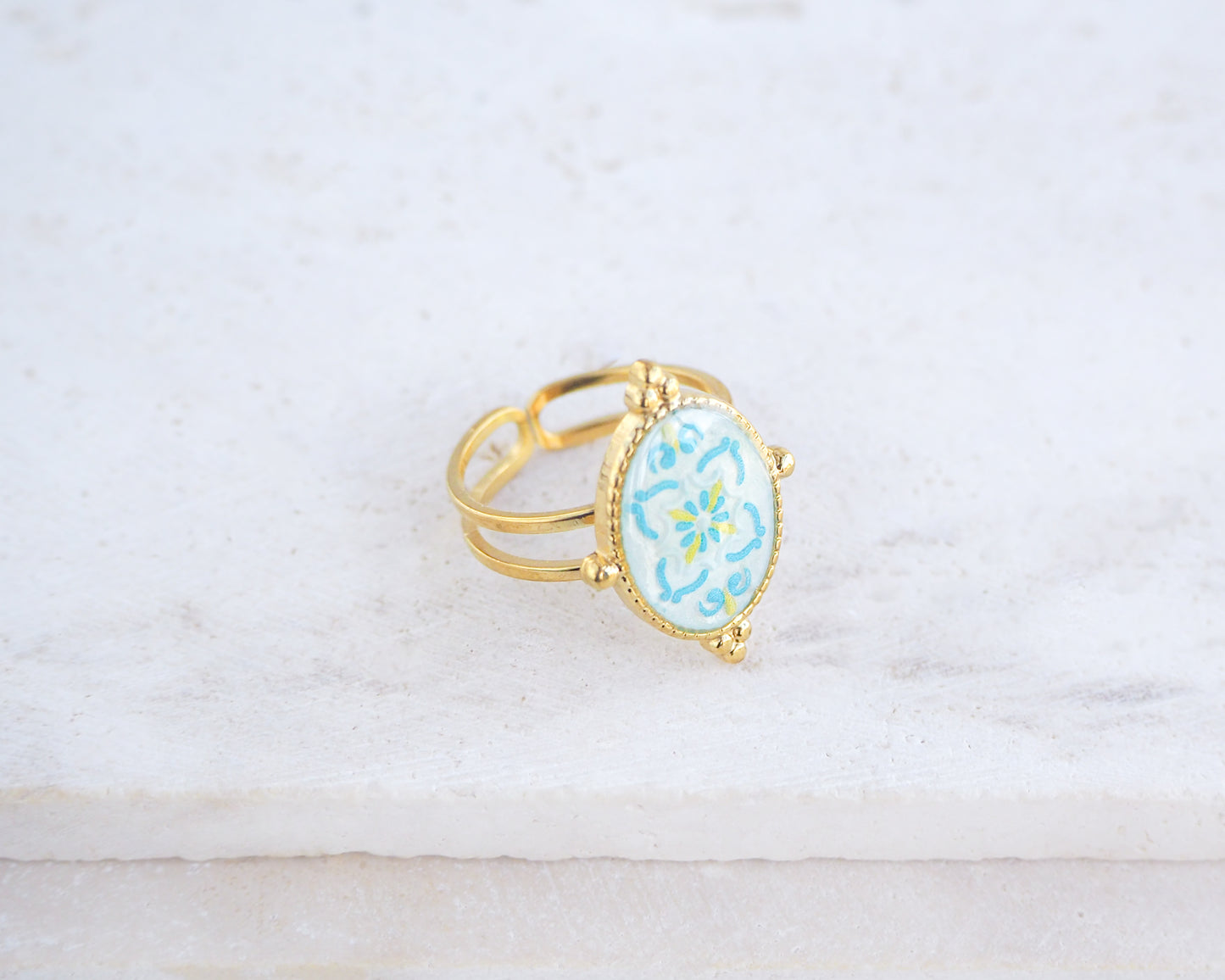 Left view of Blue Turquoise Portuguese Tile Oval Deluxe Rings on stone displayed. The ring is handmade with 18k gold stainless steel and are made with different patterns inspired by the Portuguese azulejos tiles. 