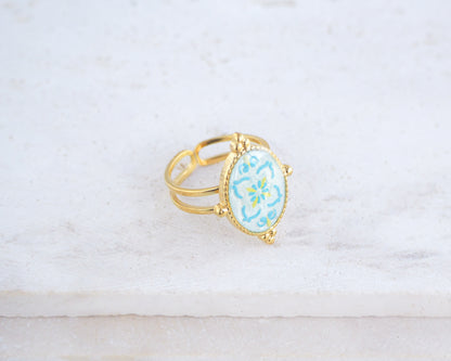 Left view of Blue Turquoise Portuguese Tile Oval Deluxe Rings on stone displayed. The ring is handmade with 18k gold stainless steel and are made with different patterns inspired by the Portuguese azulejos tiles. 
