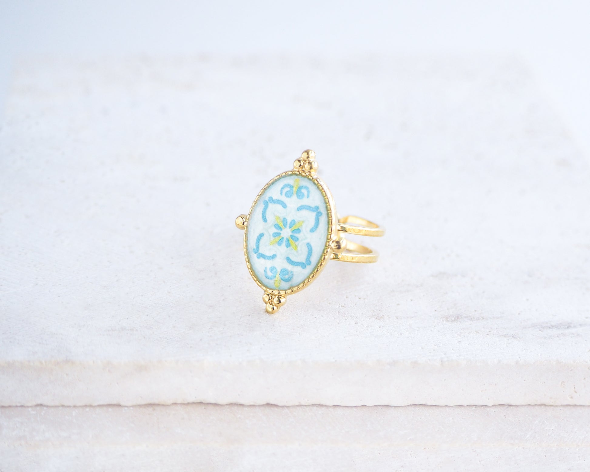 side view of Blue Turquoise Portuguese Tile Oval Deluxe Rings on stone displayed. The ring is handmade with 18k gold stainless steel and are made with different patterns inspired by the Portuguese azulejos tiles. 