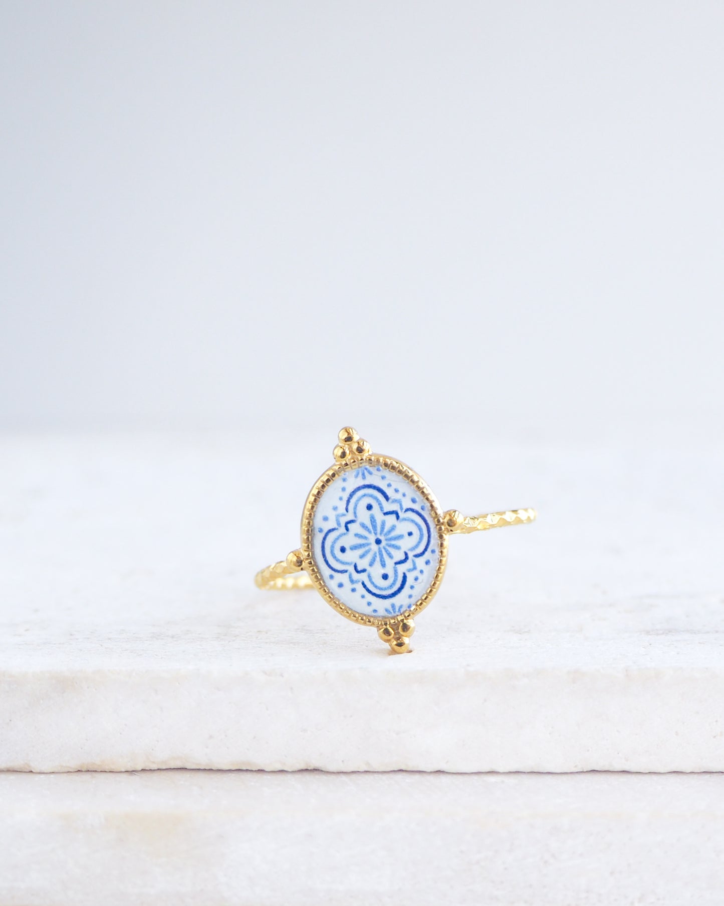 Blue White Portuguese Tile Oval Rings on stone displayed. The ring is handmade with 18k gold stainless steel and are made with different patterns inspired by the Portuguese azulejos tiles. 
