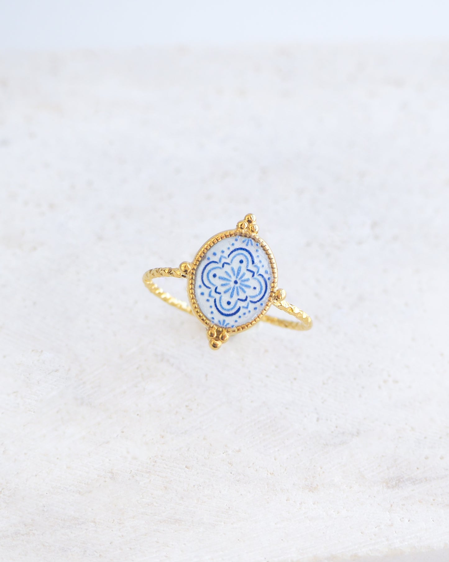 Side view of Blue White Portuguese Tile Oval Rings on stone displayed. The ring is handmade with 18k gold stainless steel and are made with different patterns inspired by the Portuguese azulejos tiles. 