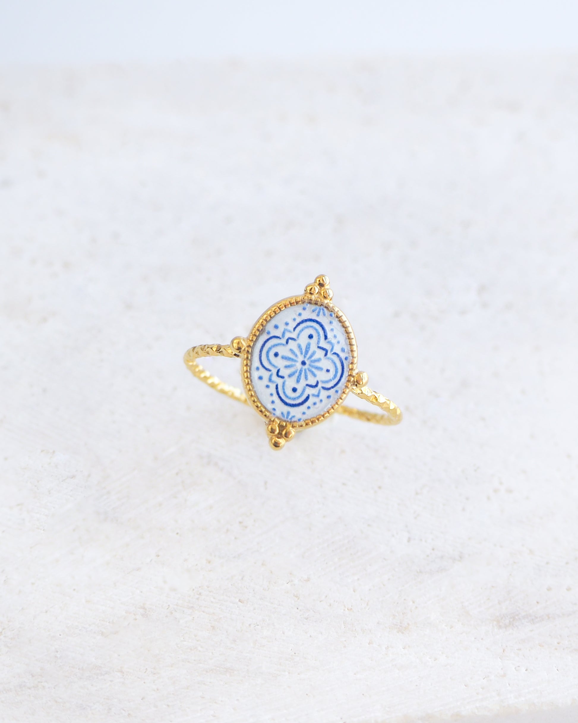 Side view of Blue White Portuguese Tile Oval Rings on stone displayed. The ring is handmade with 18k gold stainless steel and are made with different patterns inspired by the Portuguese azulejos tiles. 