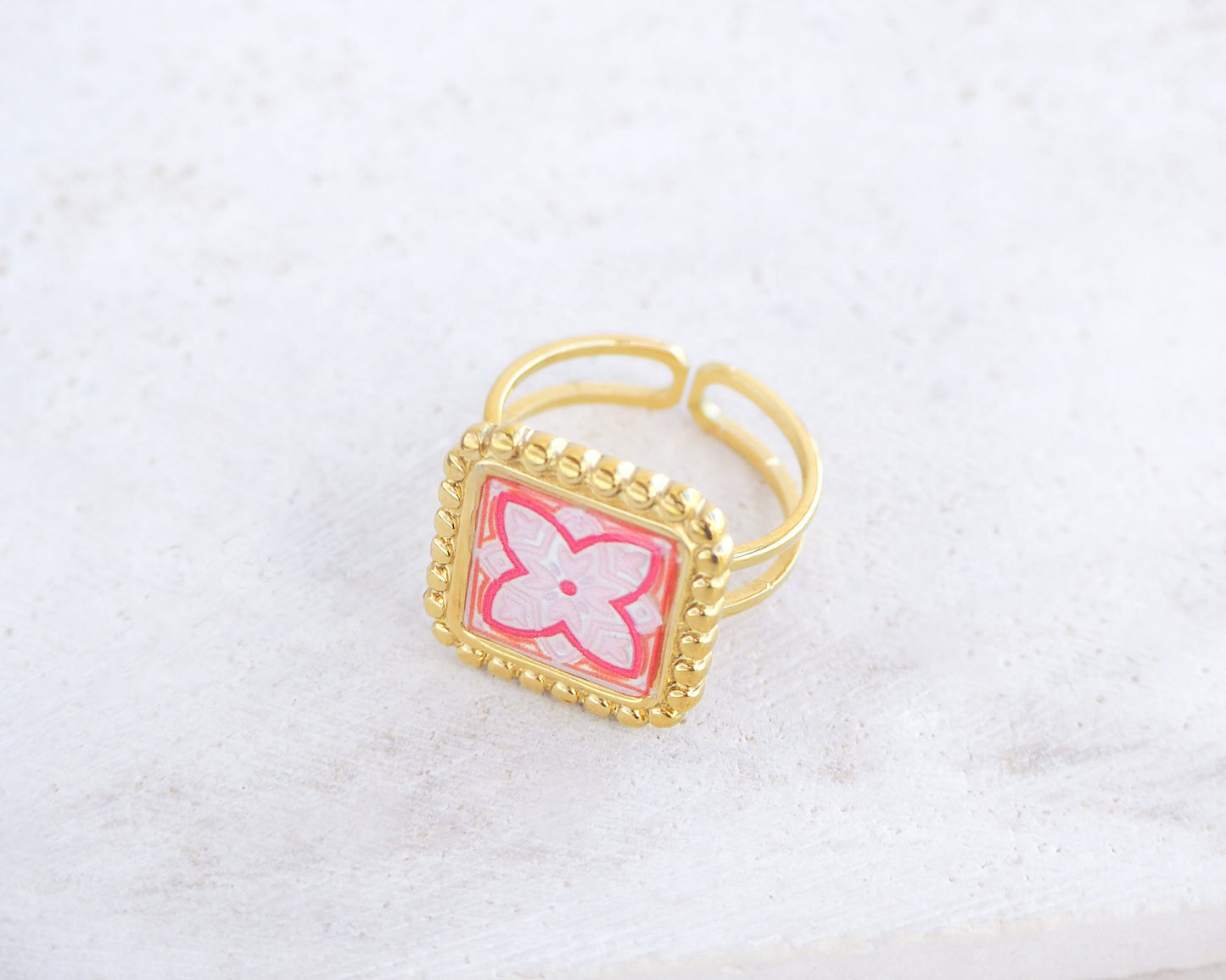 Side view of Pink orange Gold Portuguese Tile Square Ring on stone displayed. Rings is handmade with 18k gold stainless steel and has a pink orange floral tile pattern inspired by the Portuguese azulejos tiles. 