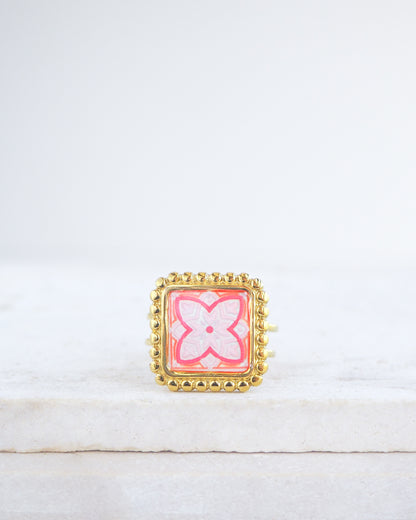 Pink orange Gold Portuguese Tile Square Ring on stone displayed. Rings is handmade with 18k gold stainless steel and has a pink orange floral tile pattern inspired by the Portuguese azulejos tiles. 