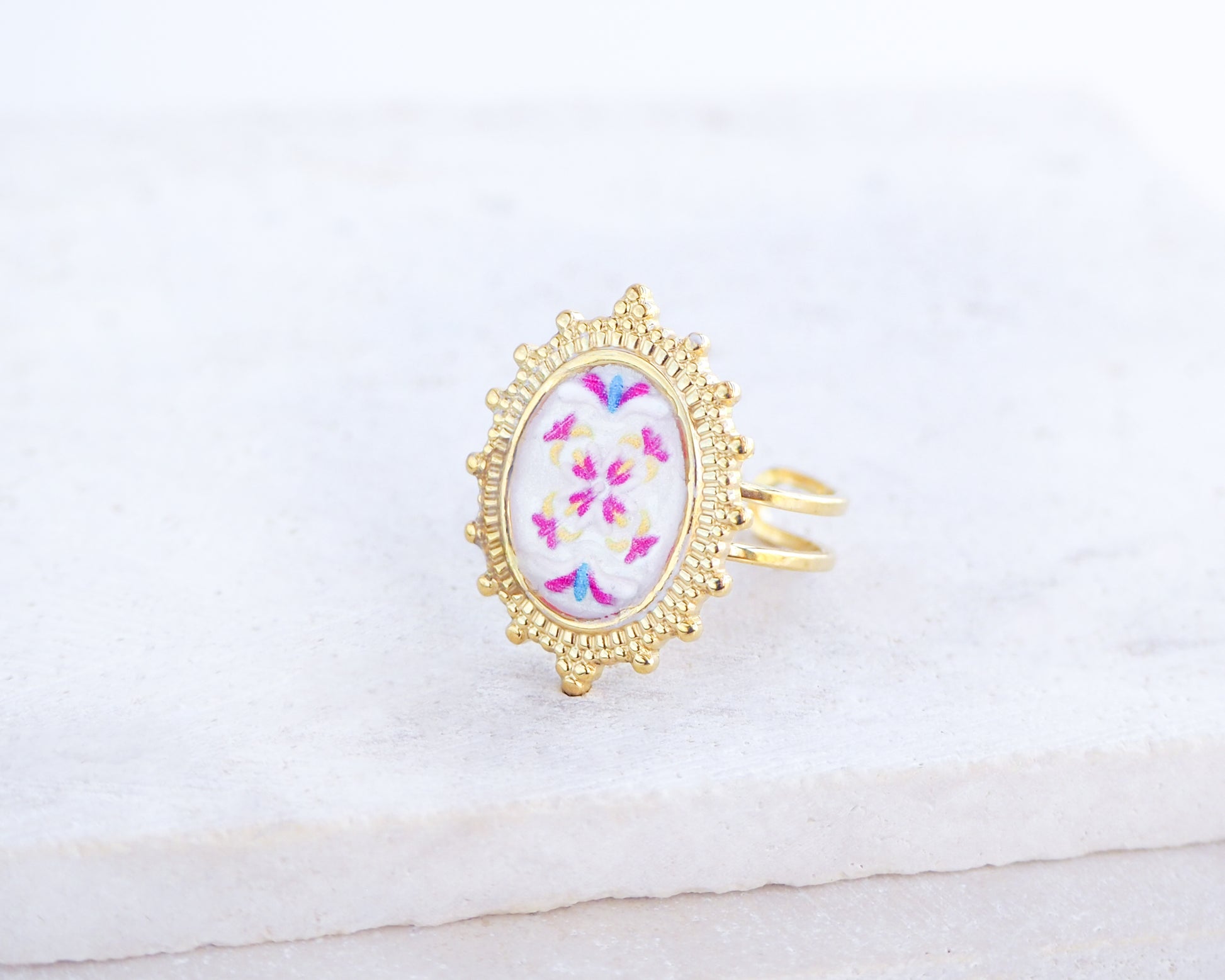 Side view of Fuchsia Portuguese Tile Oval Deluxe Rings on stone displayed. The ring is handmade with 18k gold stainless steel and are made with different patterns inspired by the Portuguese azulejos tiles. 