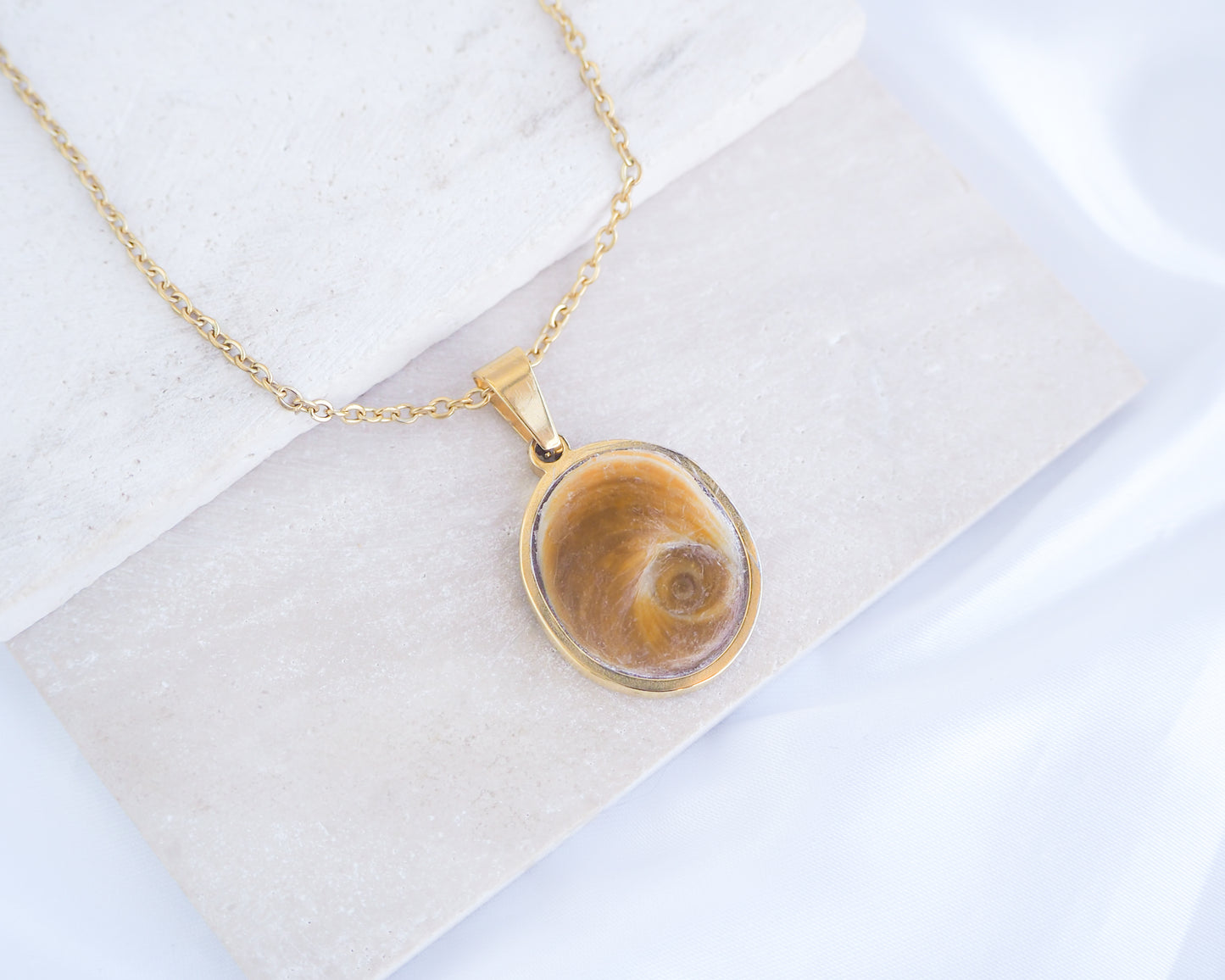 Big Brown Orange Eye of Saint Lucia Gold Necklace on stone displayed, 18k gold stainless steel brown shiva eye pendant necklace, Saint Lucy Eye, operculum pendant