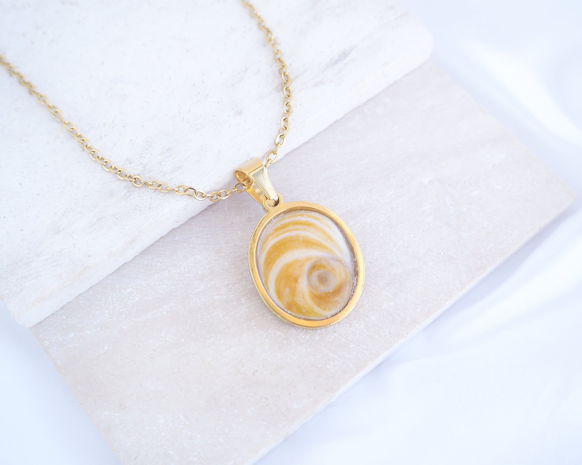 Gold Yellow Orange Shiva Eye, Eye of Saint Lucia Gold Necklace on stone displayed, 18k gold stainless steel shiva Yellow Orange eye pendant necklace, Saint Lucy Eye, operculum pendant