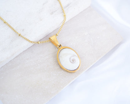White Eye of Saint Lucia Gold Necklace III on stone displayed, 18k gold stainless steel shiva eye pendant dot chain necklace, Saint Lucy Eye, operculum pendant