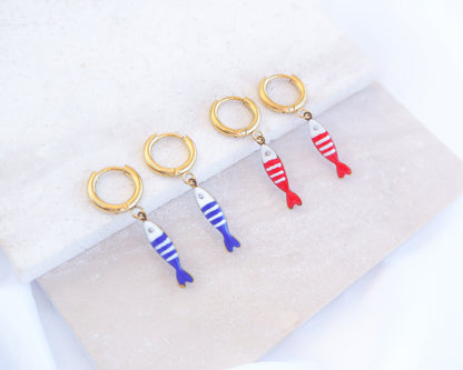 Two pairs of tiny sardine fish hoop earrings displayed on light stone. The fish pendants are red and white striped and blue and white striped. Made with 18k gold stainless steel earring hoops. Beautiful gift for Portugal lovers or holiday memory, coastal jewelry from Portugal. Nautical minimalistic jewelry 
