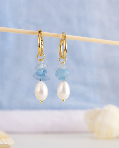 Front view of gold hoop earrings with light blue background. Made with 14k gold stainless steel, aquamarine gemstone beads and freshwater pearls.