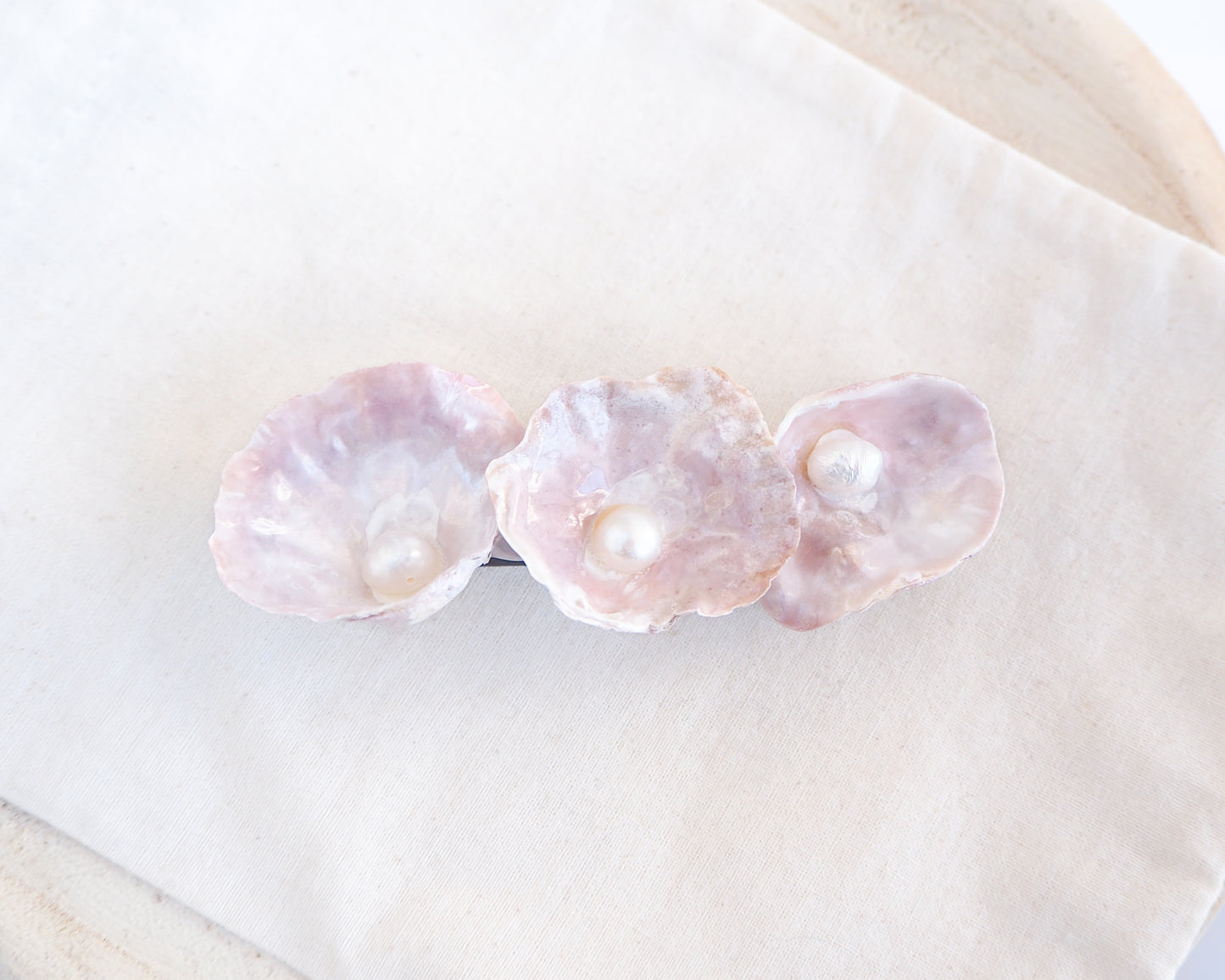 Upside down medium Pearl oyster shell hair clip with pearls on a cotton displayed. Made with handpicked jingle shells saddle oysters from Portugal. Jingle Shell Pearl Hair clip. pearly shell Hair Clip Barrette on stone displayed, Boho Seashell Beach Clip from Portugal, Handpicked Real Shells, Seashell Hair Decoration, Bohemian Seashell Wedding Hair accessories, Coastal Christmas gift, Beach Wedding Hair